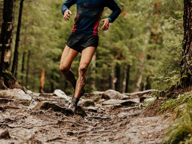 dirty runner athlete running down trail stones in woods